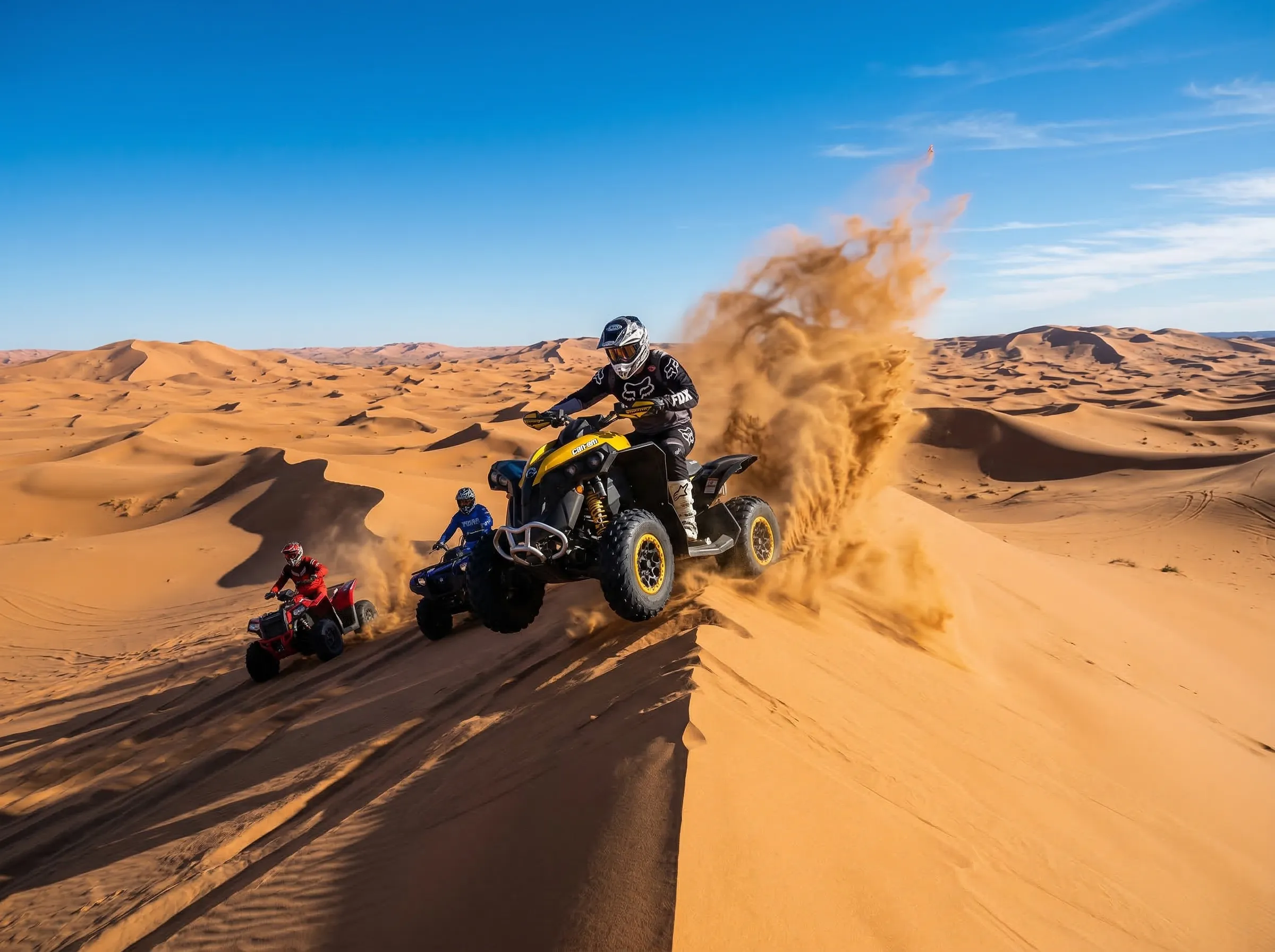ATVs cresting sand dunes in a vast desert landscape