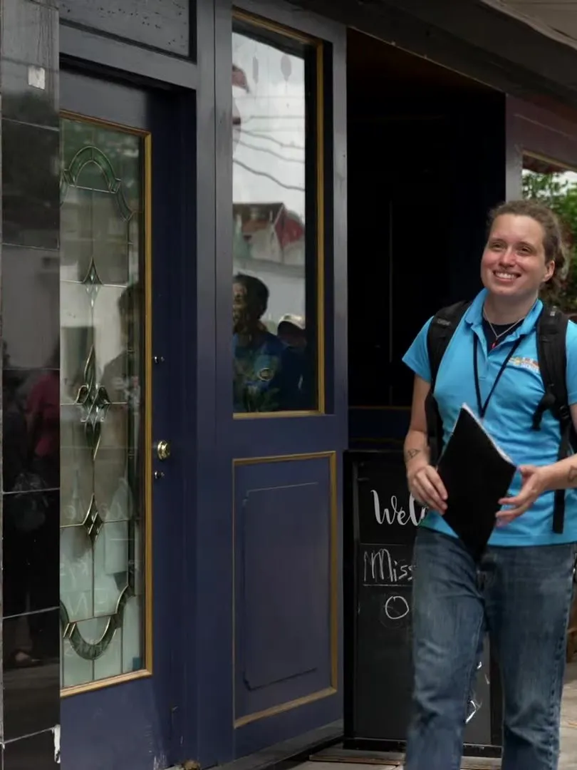 A tour guide leading a smiling group out of a restaurant